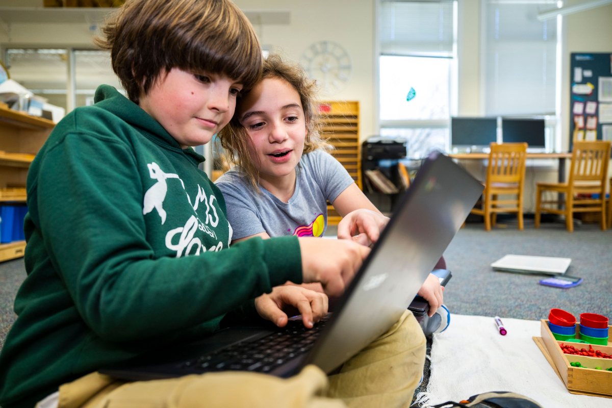 Two upper elementary students learning together on a laptop